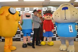 カートゥーンネットワーク（ＣＮ）初の放送について語るディー・エル・イー（ＤＬＥ）のＦＲＯＧＭＡＮ監督（中央）。右端は取材するブル男
