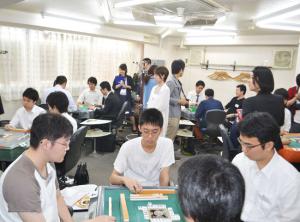 真剣な表情で対局する学生とそれを見守る各社の人事担当者