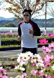 コスモス咲き乱れる道を走って宿舎へ帰る和田毅(撮影・今浪浩三)