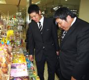 那覇空港で菓子をおいしそうに見る中田。左は赤田（撮影・清水貴仁）