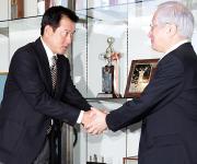 原監督(左)は気合の入った表情で加藤コミッショナーと握手を交わす