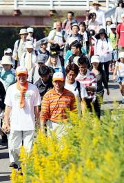 ウオーキングイベントに参加した真弓氏(中央)は笑顔を見せながら歩く