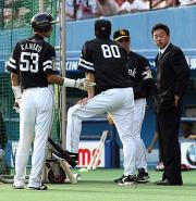 練習中に秋山総合コーチへ王監督の1日静養を伝える角田球団代表(右)
