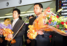 自主トレのため宮崎入りした巨人の阿部(右)は花束を抱きながらあいさつする(左)高橋由(撮影・浅見桂子)
