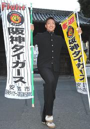 秋山は西条高の校門の前でのぼり旗を手に笑顔をみせる(撮影・河南真一)