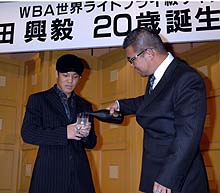 父亀田史郎さんから20年ものの焼酎を注がれる興毅(左)