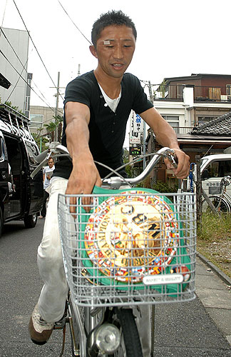 会見を終え自転車のかごにベルトを入れ笑顔を見せる内藤