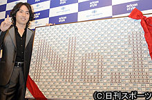 「ＮＯ・１」と描かれたオリジナルパッケージチョコ前でポーズをとる秋川雅史