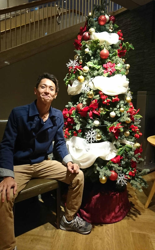 クリスマスツリーの横で笑顔の山口貢輝選手