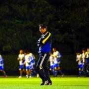 クールダウンをする選手を後方に腕を組みながらピッチを歩く岡田監督