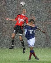 大雨の中、大宮FWラフリッチ(左)とヘディングで競り合う横浜DF中沢