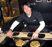 玉田は、オーナーを務める店で自らお好み焼きを焼いて笑顔をみせた