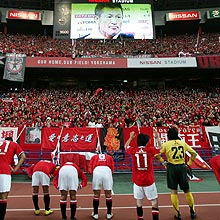 サポーターにあいさつする浦和の選手。頭上のモニターは横浜ＦＣ三浦知