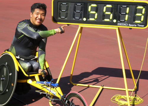 佐藤友祈は１５００メートルに続いて４００メートルでも世界新をマークし、タイム表示を指差してまた笑顔（２０１８年７月１日撮影）