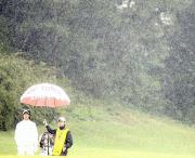 ５番、激しく降る雨の中、加藤キャディー（右）と第２打を待つ石川