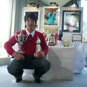 石川は優勝時の写真やトロフィーの前でポーズを取る
