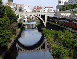 御茶ノ水駅を通過する。初夏の日差しが川面にはじけていた。後方に聖橋と丸ノ内線(亀田正人撮影)