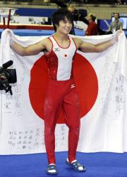 男子個人総合で優勝し、日の丸を手に喜ぶ内村航平（共同）