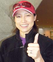 左手薬指に結婚指輪を着け、笑顔の岡崎