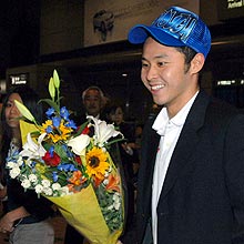 出迎えの関係者から花束をもらい、笑顔を見せる北島康介