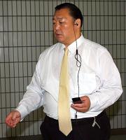 イヤホンで携帯電話を使用しながら国技館内を移動する北の湖理事長