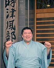 十両昇進を決め、部屋の看板の前でポーズをとる土佐豊