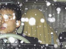 雪の中、顔を隠し名古屋地検に送検される元時津風親方の山本順一容疑者（右）