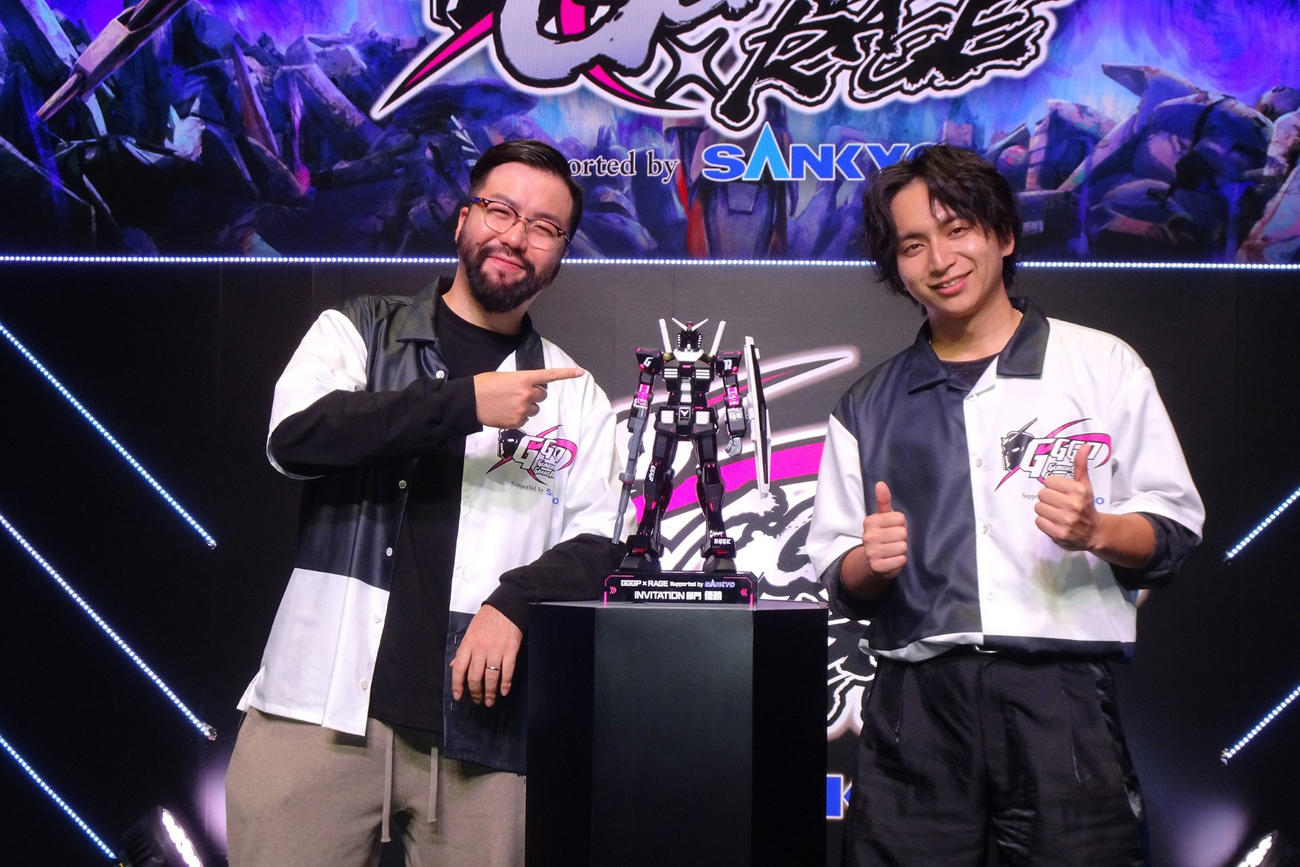 優勝したZETA DIVISIONの鈴木ノリアキ（左）とけんきは「オリジナルカラーリング ガンプラトロフィー」を前に笑顔（C）創通・サンライズ
