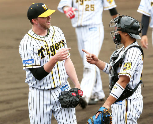 ジョンソン(右)はシート打撃の登板を終え梅野隆太郎と指さしでたたえる(撮影・上山淳一)