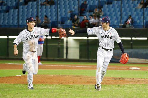 日本対プエルトリコ　5回表の登板を終えた高橋礼は好守備を見せた坂本勇（左）とタッチ（撮影・加藤哉）
