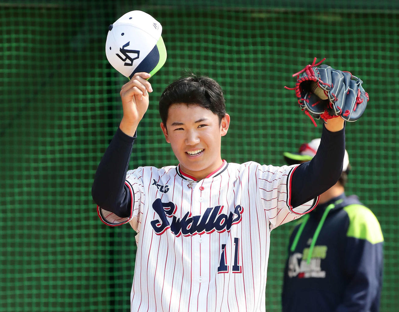 ブルペンで投球をを受けた松本捕手に帽子を取るヤクルト奥川（撮影・丹羽敏通）