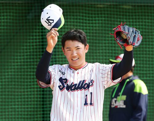 ブルペンで投球をを受けた松本捕手に帽子を取るヤクルト奥川（撮影・丹羽敏通）