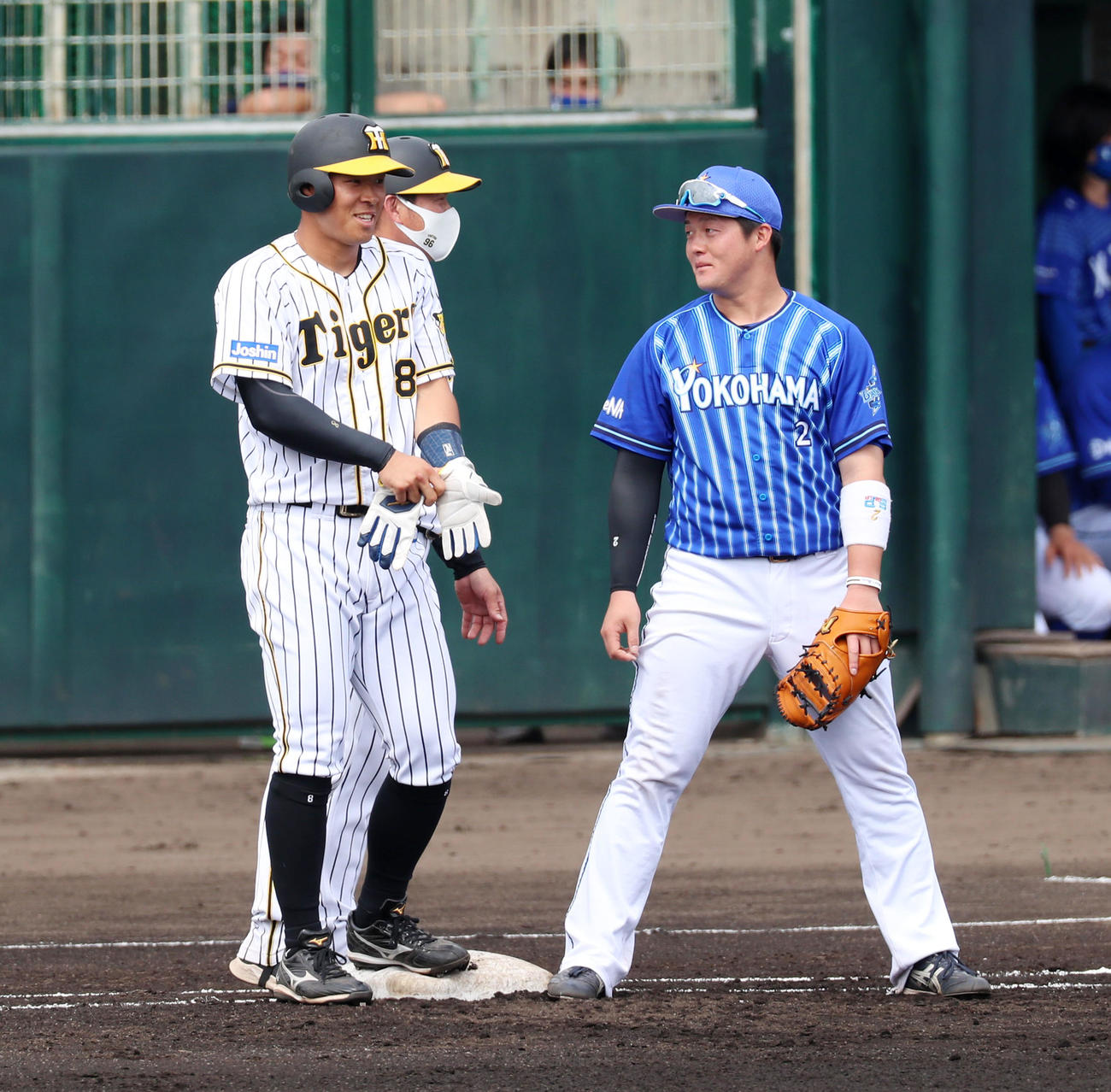 阪神対DeNA 1回裏阪神2死一塁、四球で出塁した佐藤輝は、塁上で牧（右）と会話する（撮影・加藤哉）