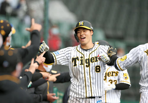 5回裏阪神無死満塁、佐藤輝は右越え満塁本塁打を放ちナインの出迎えに笑顔を見せる（撮影・上山淳一）