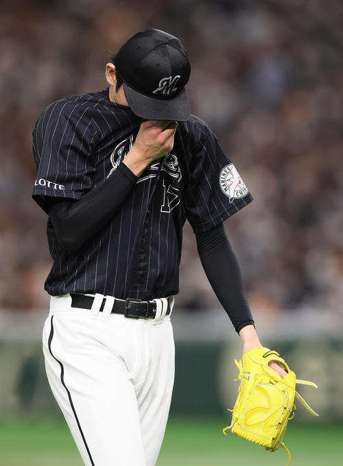 巨人対ロッテ　うつむき、汗を拭いながらベンチに戻るロッテ佐々木朗（撮影・足立雅史）