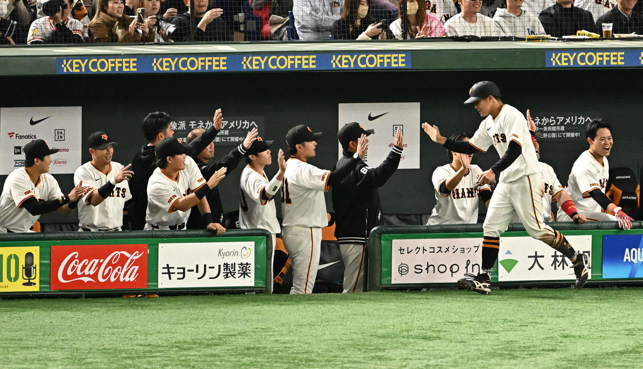 巨人対ロッテ　3回裏巨人1死一、二塁、岡本和の先制左前適時打で生還した二塁走者佐々木（手前）はチームメートとタッチをかわす（撮影・滝沢徹郎）