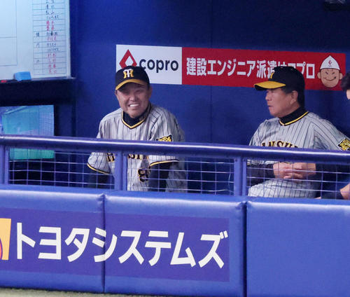 中日対阪神　6回裏を終えベンチで白い歯を見せる岡田監督。右は平田ヘッドコーチ（撮影・加藤哉）