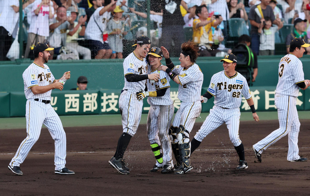阪神対広島　9回裏阪神2死二、三塁、中野はサヨナラ適時打を放ち佐藤輝（左）ら歓喜のナインと抱き合った（撮影・加藤哉）