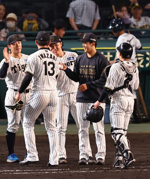 阪神対DeNA 2勝目をあげた門別（右から2人目）はは岩崎から勝利球を受け取り笑顔を見せる（撮影・上田博志）