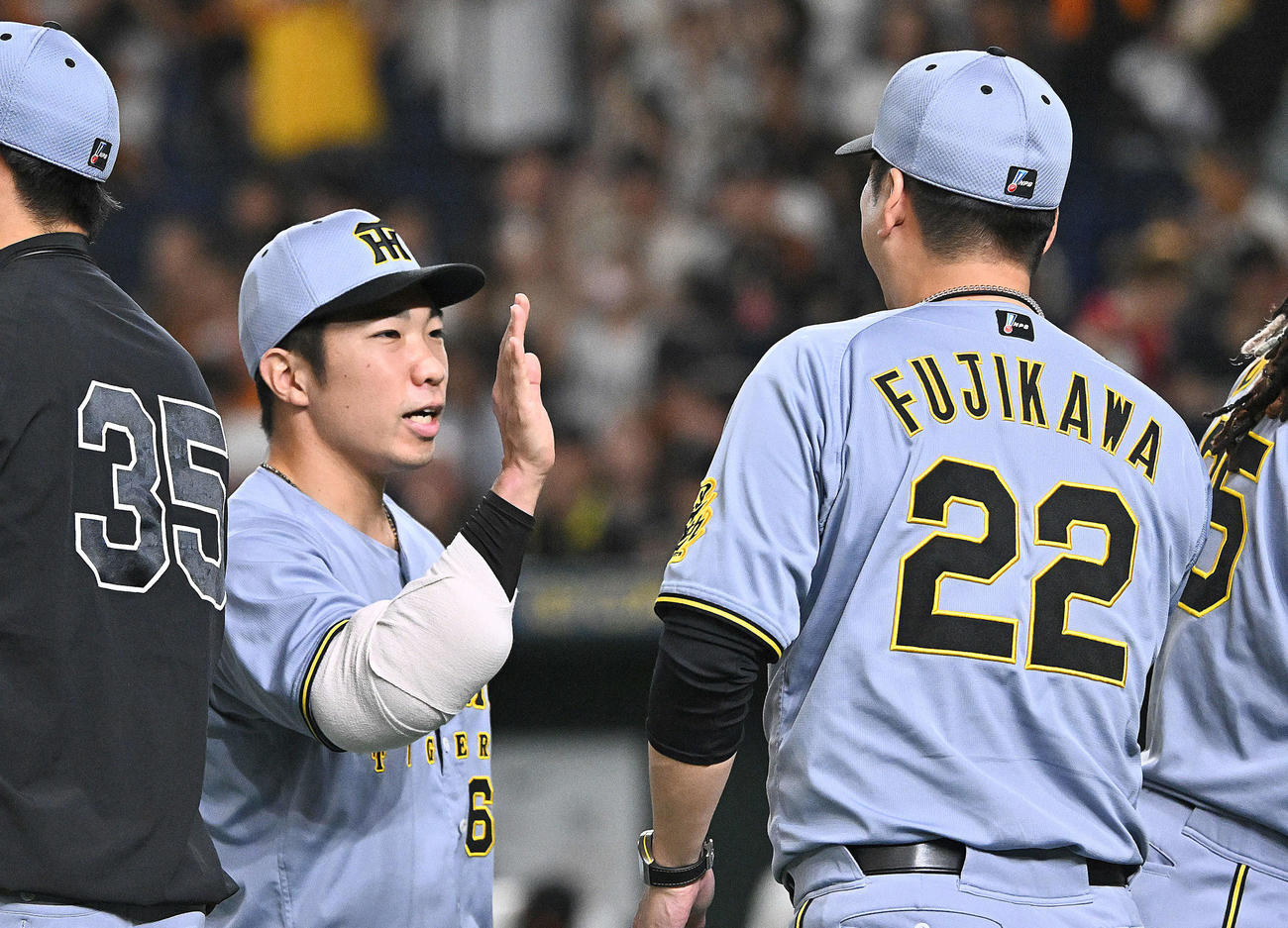 巨人対阪神　試合後、40試合連続無失点を達成した阪神石井（左）は藤川監督とタッチを交わす（撮影・滝沢徹郎）