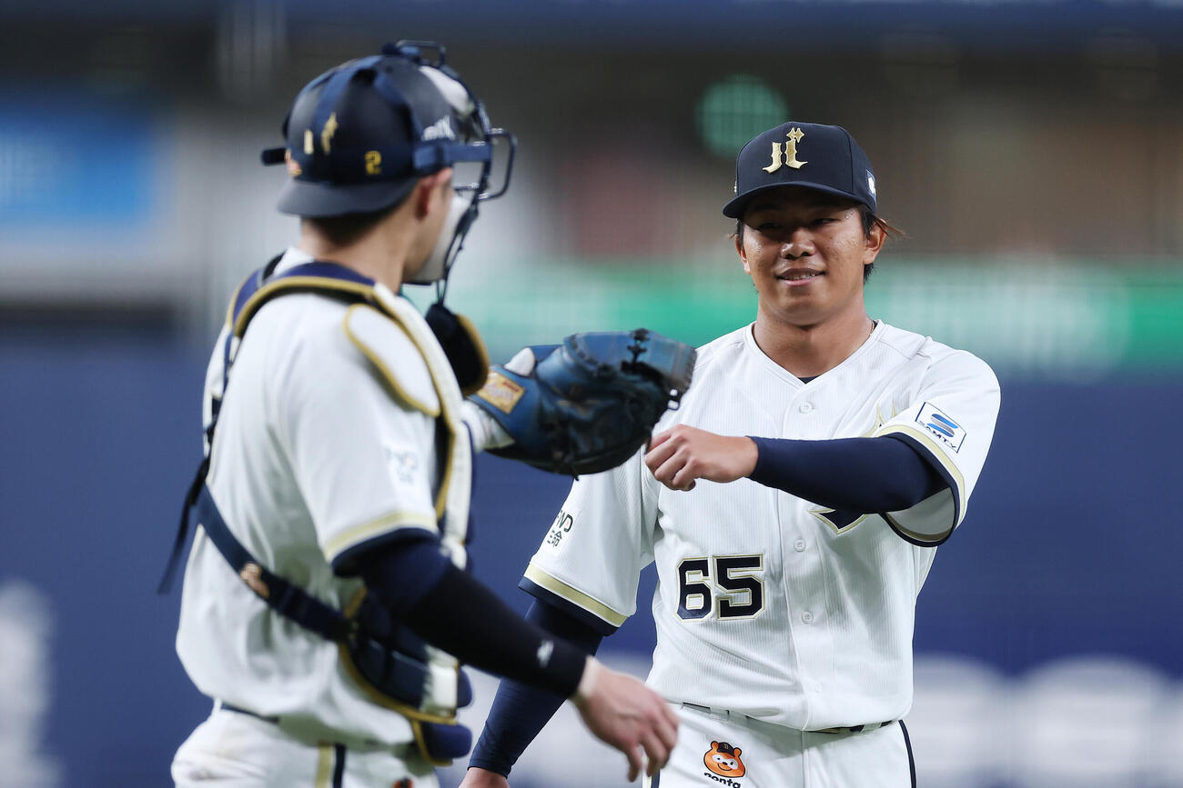オリックス対日本ハム　1回表の日本ハム打線を抑え、笑顔で若月健矢（左）とタッチを交わすオリックス宮国凌空（撮影・前田充）