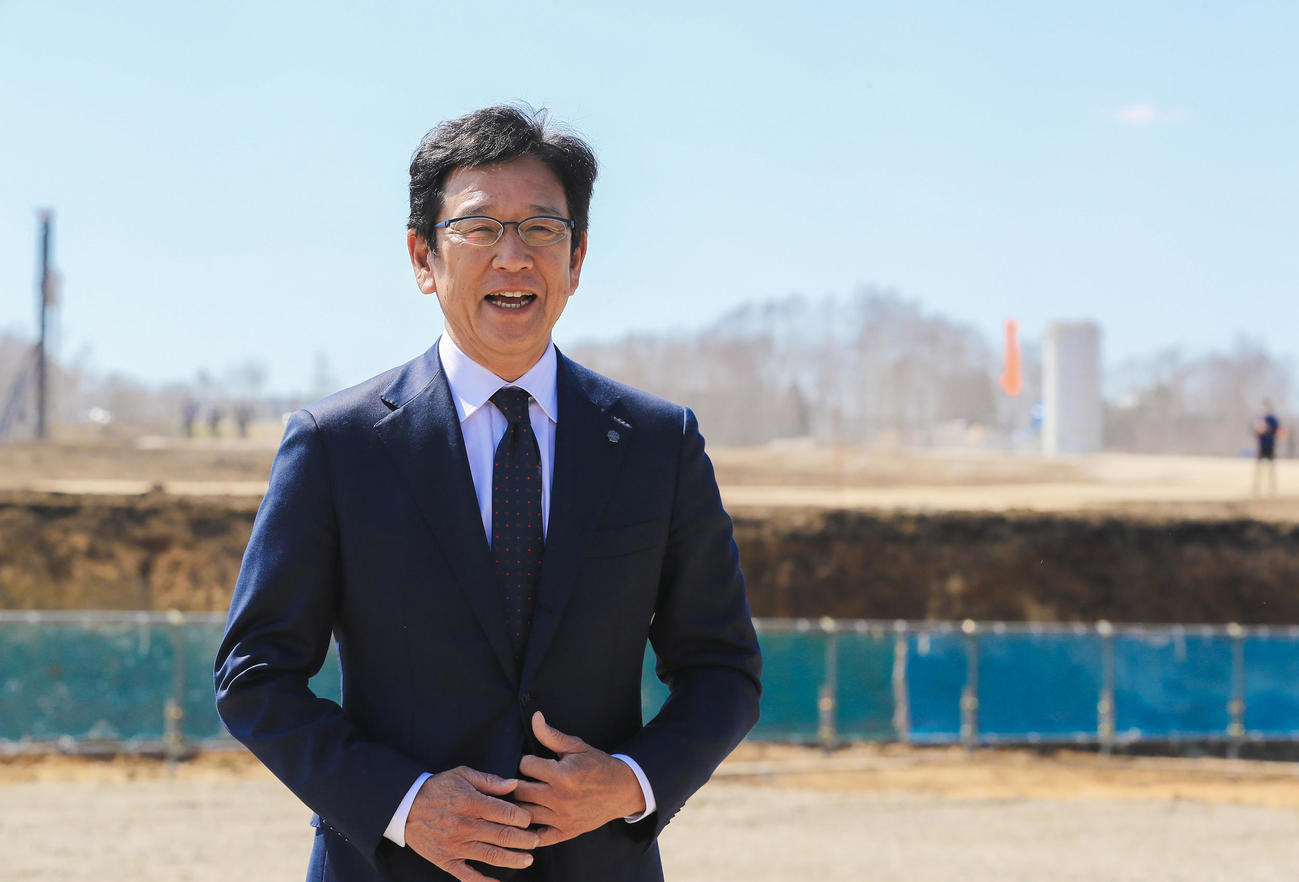 13日、新球場の起工式を終え建設現場を背に取材に応じる栗山監督