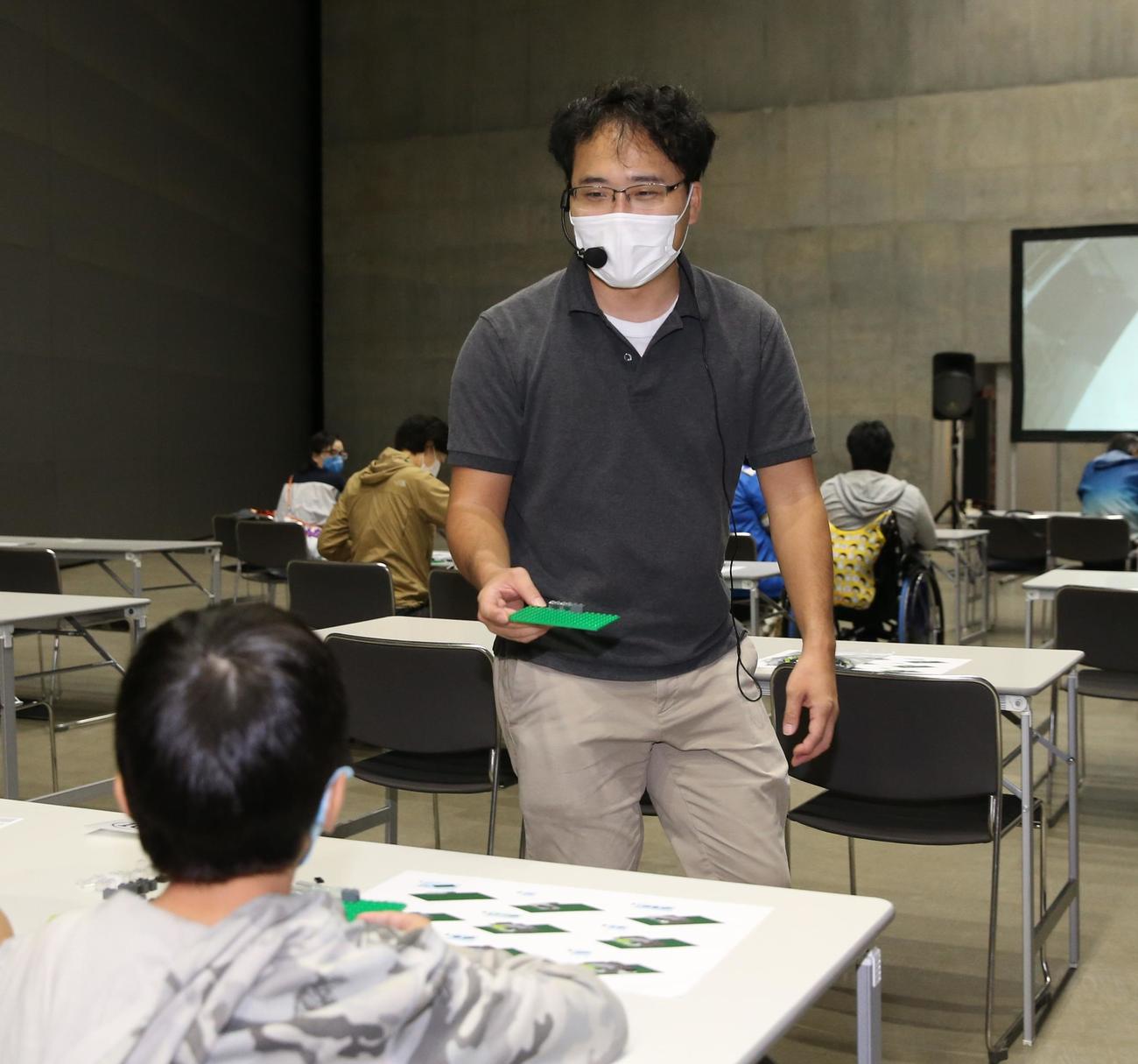 札幌ドームで行われたイベントで、子供たちにレゴブロックの作り方を指導する三井さん