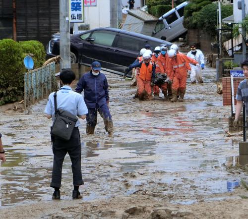 被害を受けた広島県安芸郡坂町で、家の中から発見された高齢女性の遺体を運び出す救急隊（２０１８年７月８日撮影）