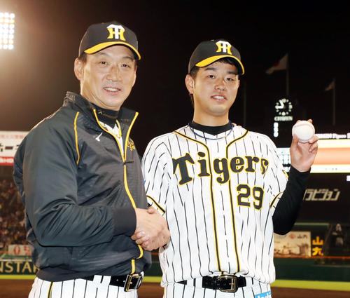 プロ初登板で初勝利を挙げた高橋遥人（右）はウイニングボールを手に金本知憲監督と握手する（2018年4月11日撮影）