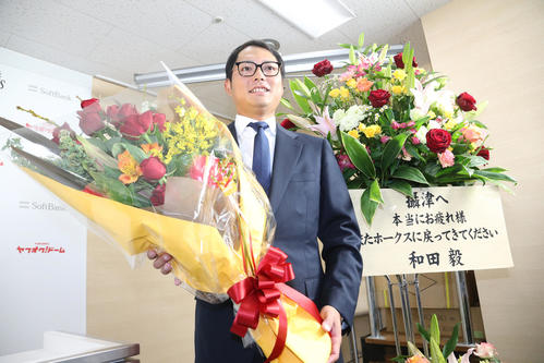 和田から贈られた花を背に笑顔を見せる摂津（撮影・梅根麻紀）