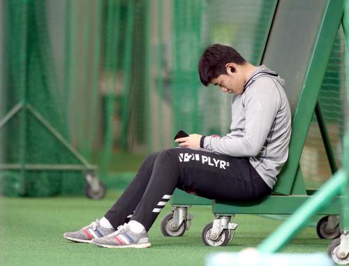 ランニング前、耳にイヤホンを付け携帯端末を操作する日本ハム清宮（撮影・黒川智章）