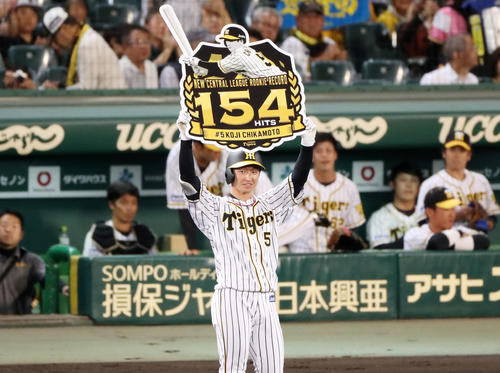 阪神対ヤクルト　1回裏阪神2死、近本は右前打を放ちセ・リーグ新人安打記録を154本に更新し記念のボードを手に笑顔を見せる（撮影・加藤哉）