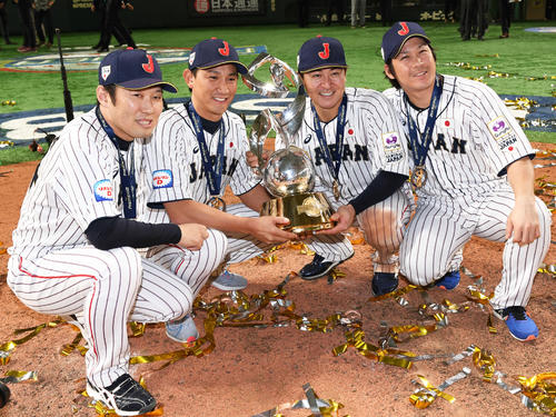 トロフィーを手に記念撮影する、左から村田コーチ、小林、会沢、甲斐（撮影・山崎安昭）