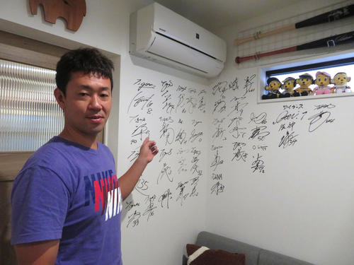 「甲子園スポーツトリートメント治療院」内にある、阪神の選手らのサインがぎっしり書かれた壁と手嶋秀和氏（撮影・磯綾乃）